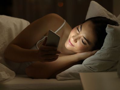 woman in bed looking at phone