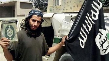 Abdelhami Abaaoud holding a Koran and an IS flag.
