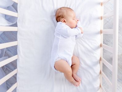 healthy sleep of a newborn baby in a cot in a bedroom on a cotton bed, top view