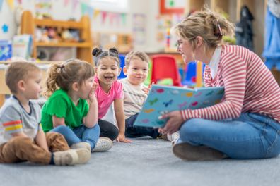 Daycare teacher sitting on the floor with preschool age children