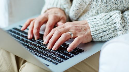 Senior older female typing on laptop keypad