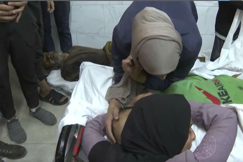 Two women look over bodies at Nasser Hospital in Khan Younis after an Israeli airstrike on November 30