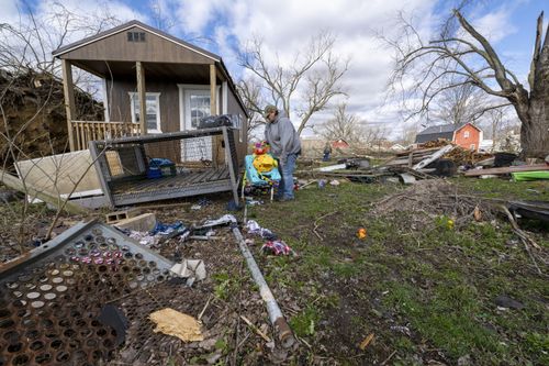 Misty Grimes, searches through debris scattered throughout her yard left from a late-night tornado in Sullivan, Ind., Saturday, April 1, 2023.