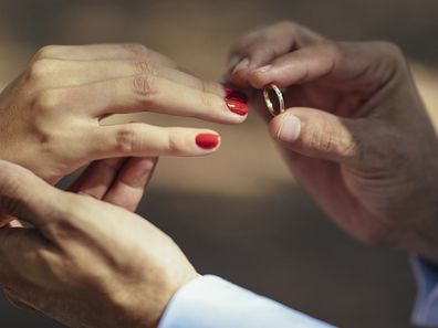 Groom putting wedding ring on finger of bride, close up