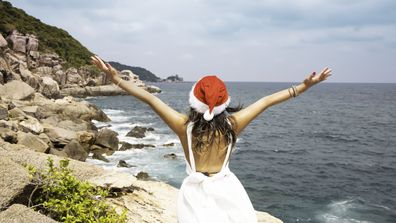 Christmas holiday santa hat with woman  in white dress which she feeling a freedom relaxing on paradise beach island
