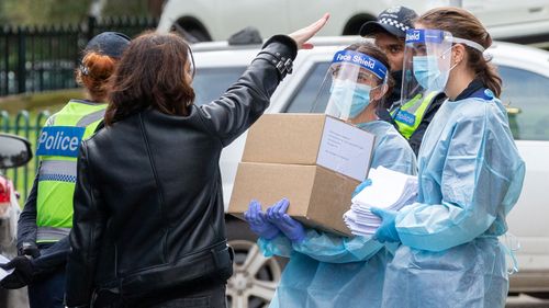 Medical staff wearing PPE deliver goods to the Flemington public housing flats.