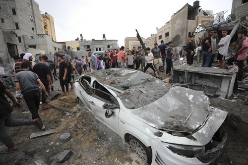 Палестинцы осматривают развалины разрушенного здания после авиаудара Израиля в Дейр-эль-Балахе в секторе Газа, пятница, 27 октября 2023 года.