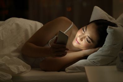 Woman using phone in bed.