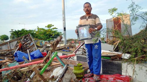 A man holds a family picture retrieved from a damaged house in Palu.