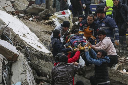 People and emergency teams rescue a person on a stretcher from a collapsed building in Adana, Turkey, Monday, Feb. 6, 2023
