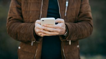 Young man holding smart phone reading text.