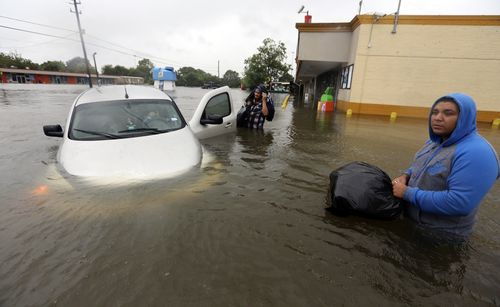 Conception Casa, center, and his friend Jose Martinez, right, check on Rhonda Worthington after her car become stuck. (AP)