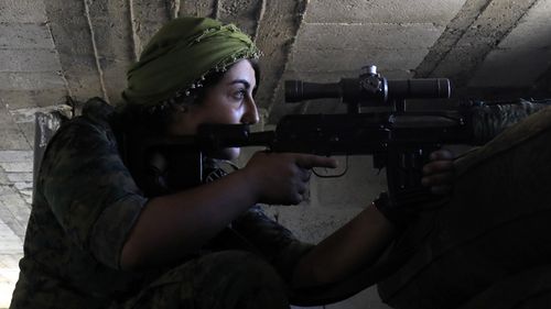 A female member of the Syrian Democratic Forces, a US-backed Kurdish-Arab alliance, holds a position inside a building in an area close to the Old City in the embattled northern Syrian city of Raqa on September 3, 2017, as they battle to retake the city from the Islamic State group. (AFP)