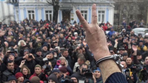 Mikheil Saakashvili shows the peace sign to supporters outside his apartment in Kiev. (AAP)