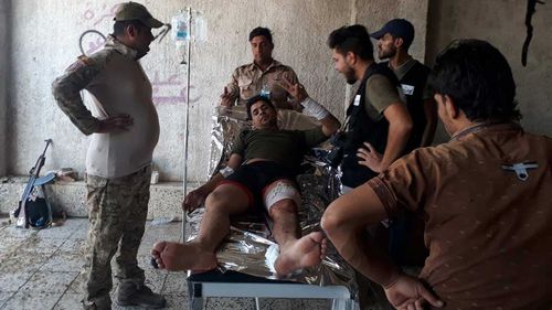 An injured man gestures to the camera in Mosul. (Owen Holdaway)