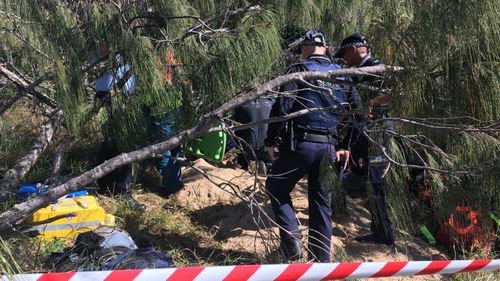 Emergency services are working to free a man stuck in sand up to his neck at a Queensland beach.