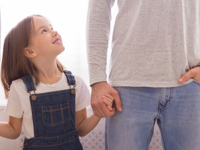 Family Protection. Happy Little Girl Holding Hands With Parents And Looking Up At Father, Cropped Image