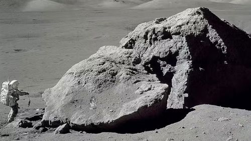 Apollo 17 astronaut Harrison H. Schmitt walks near a massive rock on the moon in 1972, in what was the final mission of NASA's Apollo program.