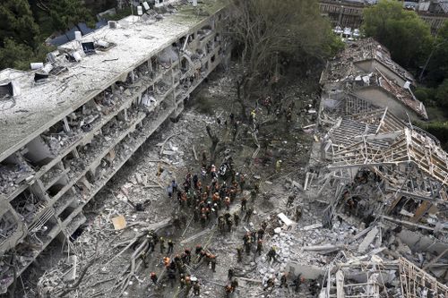 Kurtarma çalışanları ve itfaiyeciler, İran'dan atılan bir füze sonrası Tel Aviv'deki yeri inceliyor.