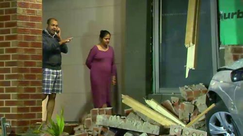 Amit Saraf and his pregnant wife inspect the damage to the home's exterior. (9NEWS)