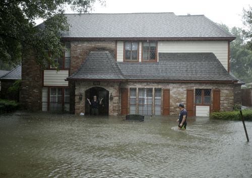 A man standing in the doorway of his flooded home responds to an evacuation offer in a neighbourhood inundated by floodwaters. (AP)