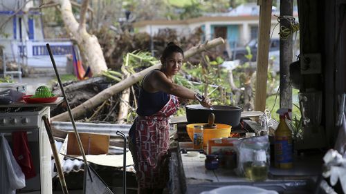 Margarita Burgos cooking outside over a wood fire, due to the lack of cover and electricity in Yabucoa. (AAP)