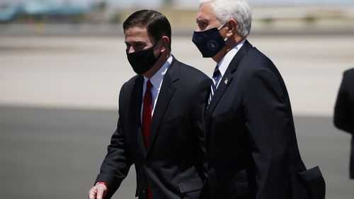 Vice President Mike Pence, right, walks with Arizona Gov. Doug Ducey, left, as the two head to a meeting to discuss the surge in coronavirus cases.