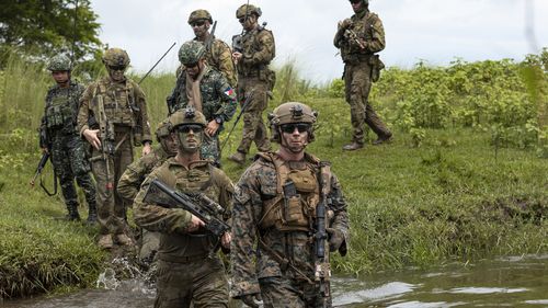A Commanding Officer of the 1st Battalion, the Royal Australian Regiment Lieutenant Colonel Brent Hughes (centre) moves across a waterway with United States Marines and Armed Forces of the Philippines soldiers during a large-scale combined amphibious assault exercise on Friday, Aug. 25, 2023, at a naval base in San Antonio, Zambales, Philippines.