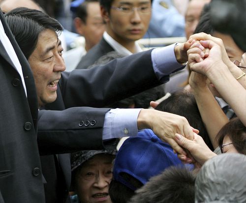 Japan's Chief Cabinet Secretary Shinzo Abe, left, reaches out for his supporters during his public speeches at Shibuya railway station in Tokyo Saturday, Sept. 16, 2006.
