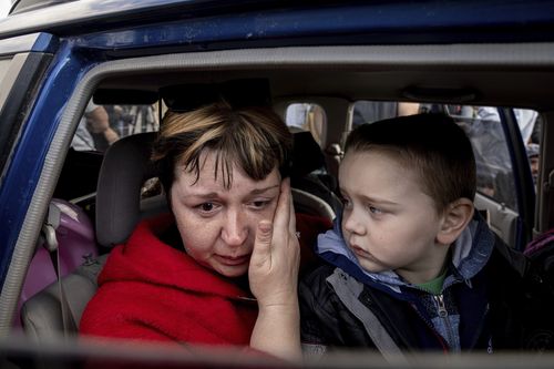 Natalia Pototska, 43, cries as her grandson Matviy looks on in a car at a center for displaced people in Zaporizhzhia, Ukraine, Monday, May 2, 2022. (AP Photo/Evgeniy Maloletka)