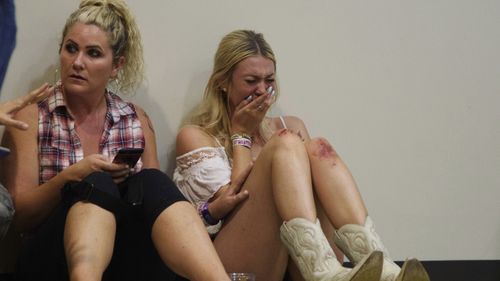 A woman cries while hiding inside the Sands Corporation plane hangar after the mass shooting. (AAP)