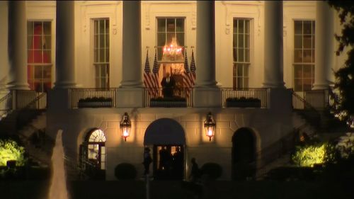 Donald Trump stands on a balcony outside the White House.