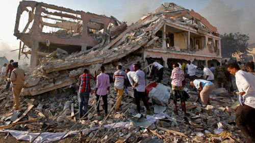 Somalis gather and search for survivors at buildings destroyed by the blast. (AAP)