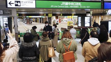 People gather in front of a ticket gate at a station as train services are suspended following an earthquake in Sendai, Miyagi prefecture, Japan Saturday, March 20, 2021