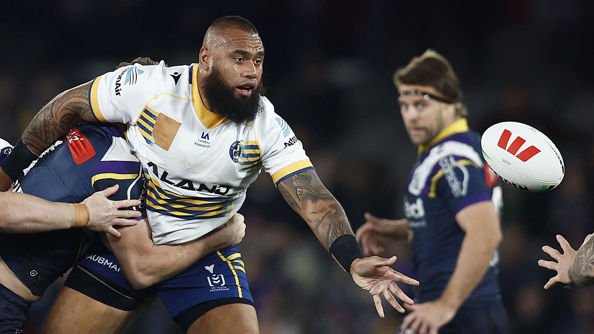 Junior Paulo of the Eels passes the ball whilst being tackled.