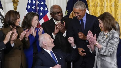 President Joe Biden looks to former President Barack Obama after signing an executive order 