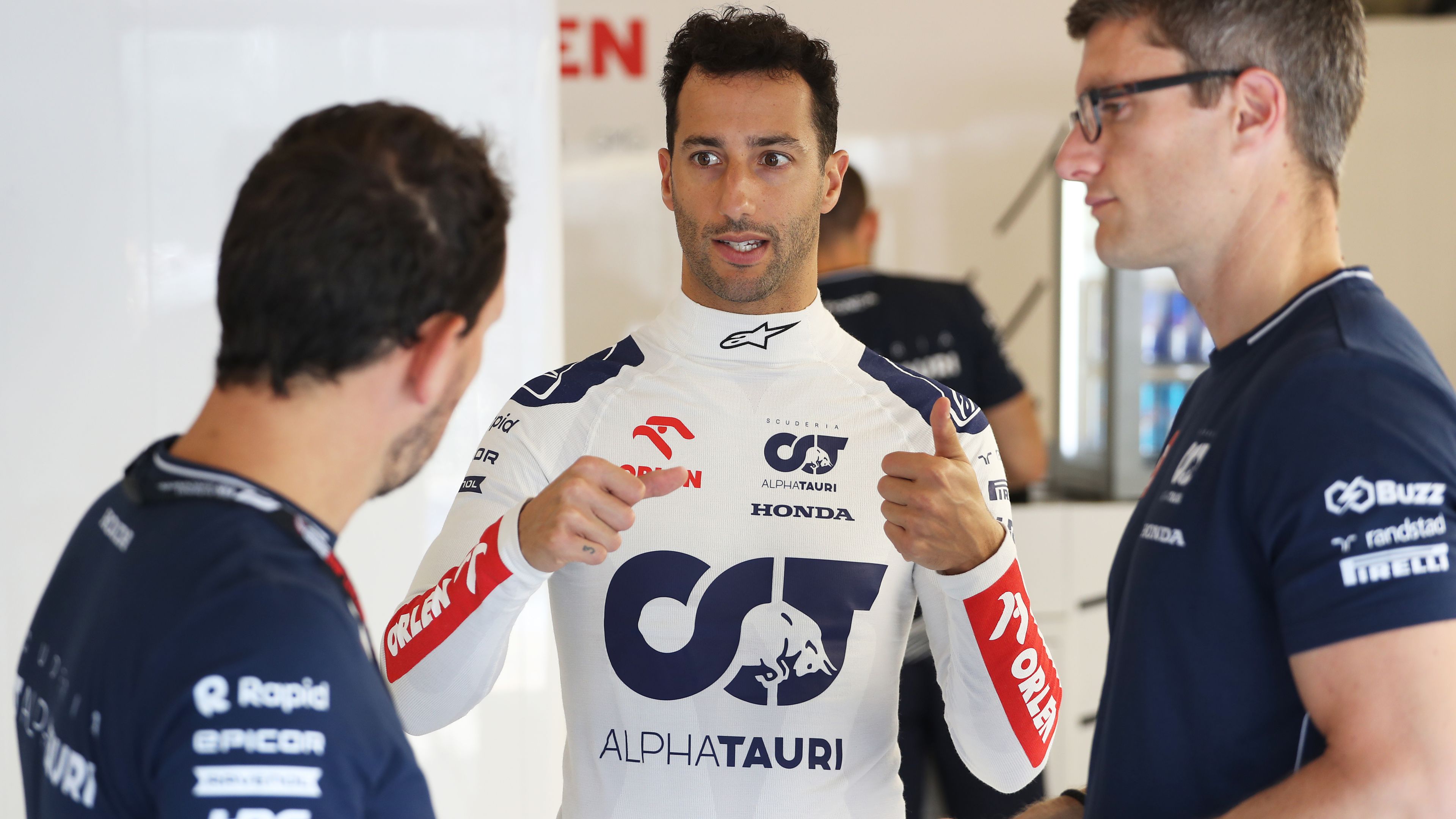 Daniel Ricciardo of Australia talks with the Scuderia AlphaTauri team in the garage during previews at Hungary.
