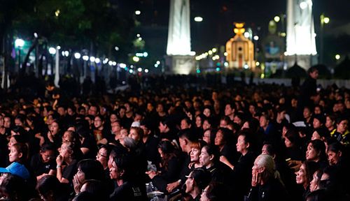 Thai mourners gather to watch the royal cremation ceremony of the late Thai King Bhumibol Adulyadej, displayed on a big-scale screen on a main road near the Royal Crematorium in Bangkok.
(Photo: EPA).