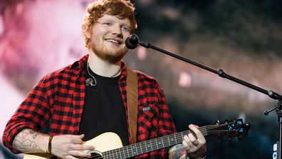 Ed Sheeran playing guitar with mic at concert 