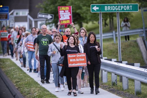 Oamenii merg pe o stradă locală la sfârșitul unei privegheri în solidaritate cu familiile din Ovaldi, Texas, și cer încetarea violenței cu armele de joi, 26 mai 2022, în Newtown, Connecticut.