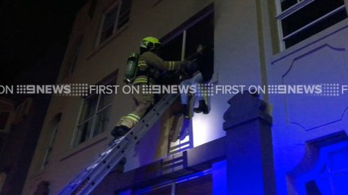 A firefighter rescues a woman from the first floor of an apartment block in Bondi. 