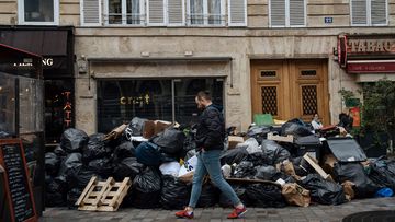 A man walks past uncollected garbage in Paris, Monday, March 13, 2023.