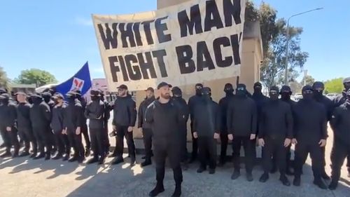 About 50 people — masked, dressed in black and brandishing a neo-Nazi banner that read "white man fight back" — held a demonstration in front of a war memorial in the small border town of Corowa on Saturday. ﻿