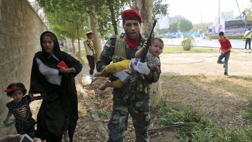 An Iranian army member carries away a child from a shooting scene during a military parade marking the 38th anniversary of Iraq's 1980 invasion of Iran, in the southwestern city of Ahvaz, Iran. (AP)