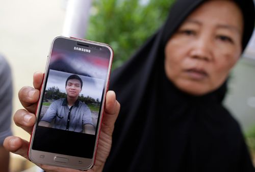 Yeni, 47, shows a picture of her son Muhammad Rafi, one of the plane crash victims, as relatives wait for the news of the forensics inspection in Jakarta.