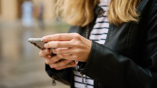 Close up shot of woman using smartphone on city street. Mobile phone in female hands outdoors