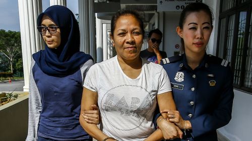 Australian Maria Elvira Pinto Exposto is escorted by police outside the magistrate court in Sepang.