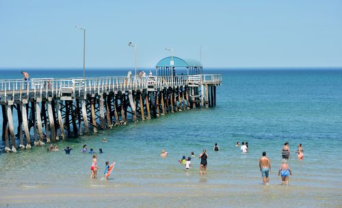 Beachgoers cool down in the water beside Henley Jetty in Adelaide. (AAP)