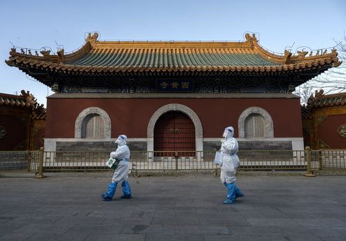 2022 年 12 月 3 日，在中国北京，流行病控制人员在经过黄寺寺对被封锁或健康监测的 COVID-19 人员进行核酸检测时穿着 PPE。  （凯文弗雷尔/盖蒂图片社摄）