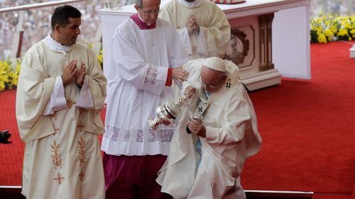 The Pope is helped back to his feet by altar services. (AAP)